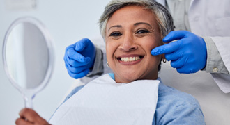 Woman smiling while holding small mirror in treatment room