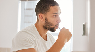 Closeup of man brushing his teeth in bathroom
