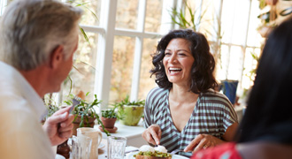 Woman smiling while eating with friends in restaurant