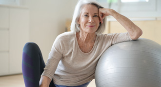 Woman resting against yoga ball in workout room