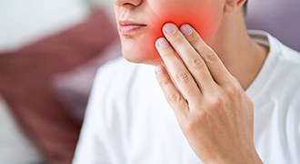 A man touching his reddened cheek due to a toothache