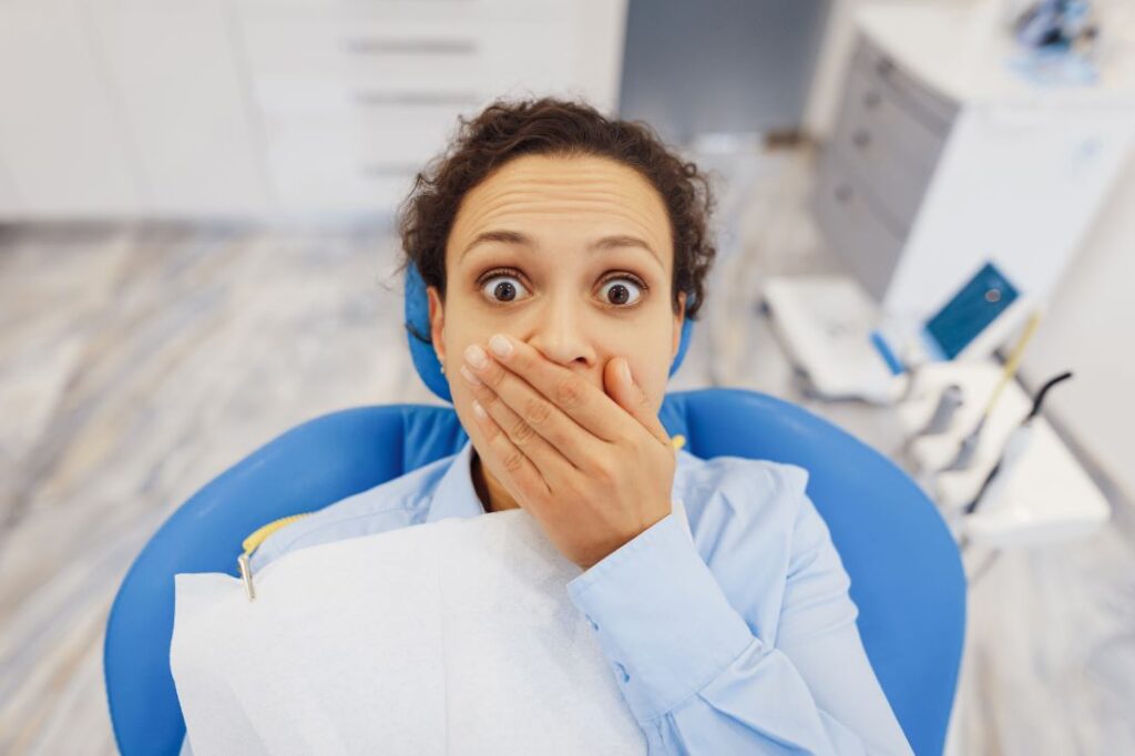 A woman covering her mouth in a dentist's chair.